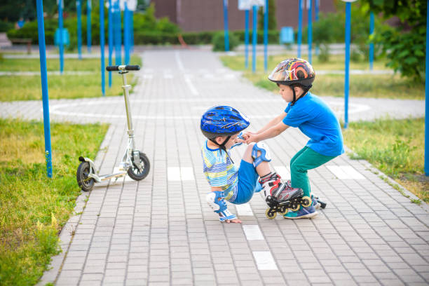 istock two boys in park, help boy with roller skates to stand up 1210046468