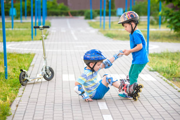 istock two boys in park, help boy with roller skates to stand up 1210046479