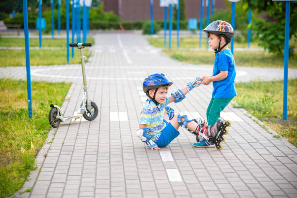 istock two boys in park, help boy with roller skates to stand up 1210046485
