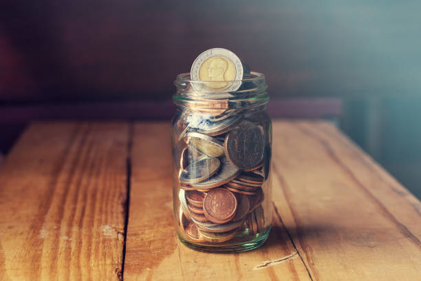 istock Saving money in glass jar on wood background. 1210046496