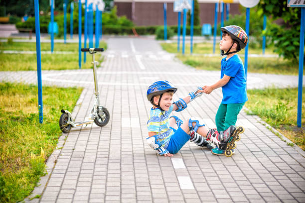 istock two boys in park, help boy with roller skates to stand up 1210046500