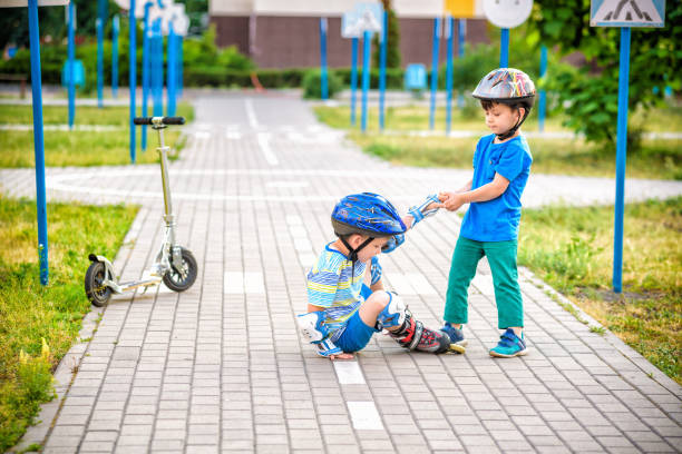 istock two boys in park, help boy with roller skates to stand up 1210046507