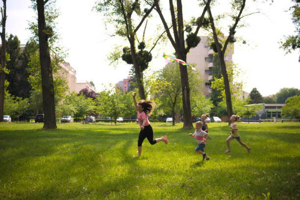 istock Happy kids having fun while flying a kite in the park. 1210048248