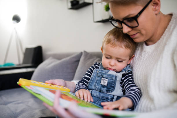 istock mom read book with son and sit on sofa at home 1210049379