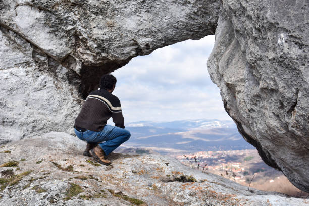 istock Young hiker looking through natural window in cliff 1210049620
