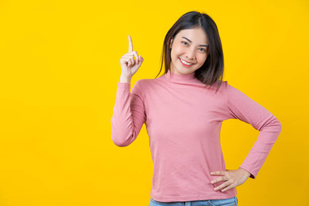 asian smiling young woman finger pointing up for advertise - pointing women cheerful front view imagens e fotografias de stock