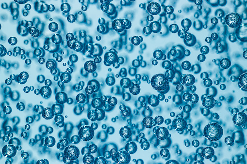 Macro shot of air bubbles in transparent gel, blue background. Many spheres reflecting each other. Abstract pattern