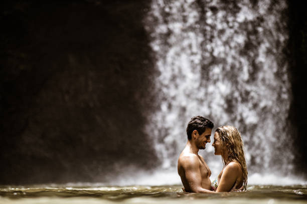 istock Young happy couple talking in water at rainforest. 1210054146