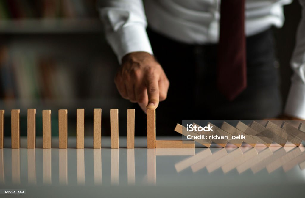 Businessman Stop Domino Effect. Risk Management and Insurance Concept Risk Stock Photo