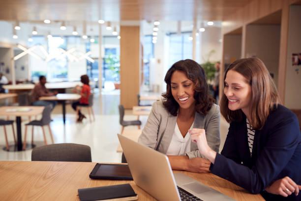 istock Two Businesswomen With Laptop At Desk In Open Plan Office Collaborating On Project Together 1210054733