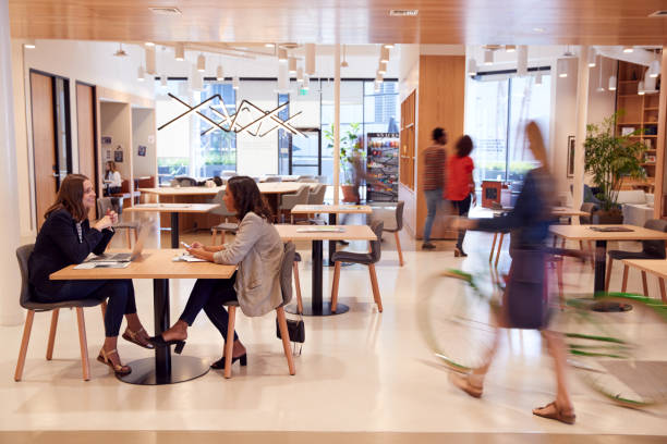 Interior Of Modern Open Plan Office With People Working And Commuters Arriving On Bikes Interior Of Modern Open Plan Office With People Working And Commuters Arriving On Bikes open plan stock pictures, royalty-free photos & images