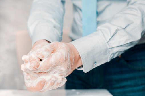 Businessman in blue shirt and tie wash his hands deeply. Hand washing is very important to avoid the risk of contagion from coronavirus and bacteria.