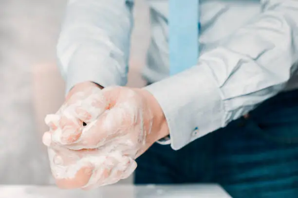 Photo of Businessman in blue shirt and tie wash his hands deeply. Hand washing is very important to avoid the risk of contagion from coronavirus and bacteria.