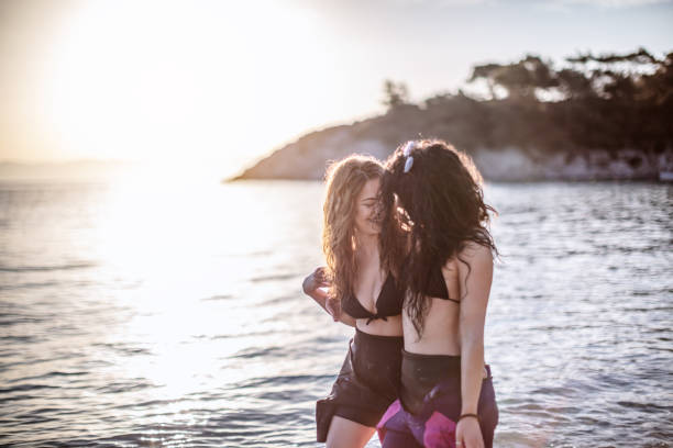 Smiling girlfriends spending time on the beach in surf suit