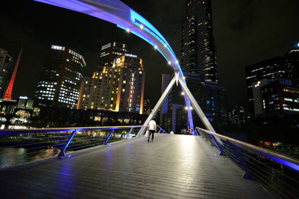 Man walking on Evan Walker pedestrian bridge over the Yarra river, Victoria, Australia.