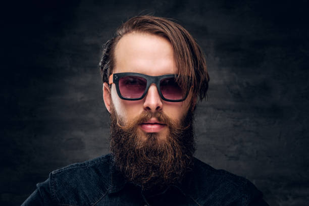 istock Attractive bearded man in sunglasses over dark background. 1210058540
