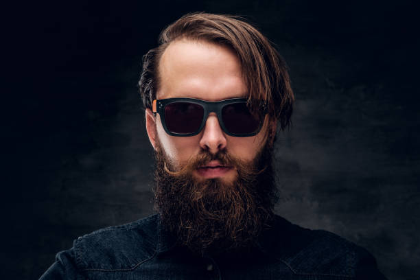 istock Attractive bearded man in sunglasses over dark background. 1210058575