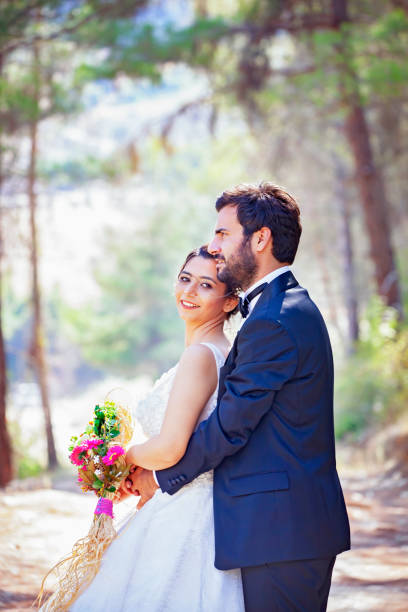 The bride and groom posing in nature. Portrait of an attractive couple in forest. Wedding ceremony. Newlyweds getting married outdoors. Retro style photos.