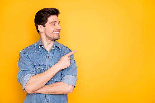 Portrait of nice attractive content cheerful cheery guy pointing forefinger, aside advert copy empty black place space follow subscribe isolated over bright vivid shine vibrant yellow color background