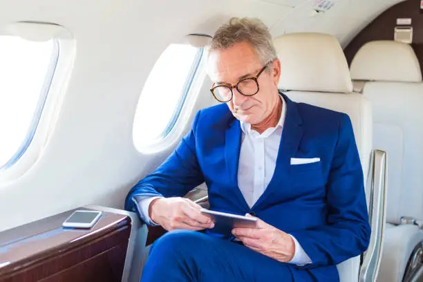 Photo of Senior businessman traveling by corporate jet