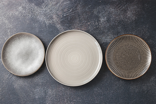 Top view of three empty plates isolated on dark background