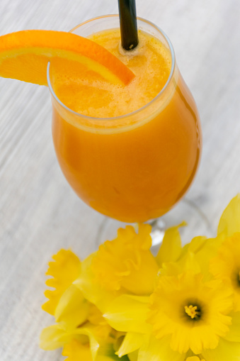 Vaso de zumo de naranja con flores en la mesa photo