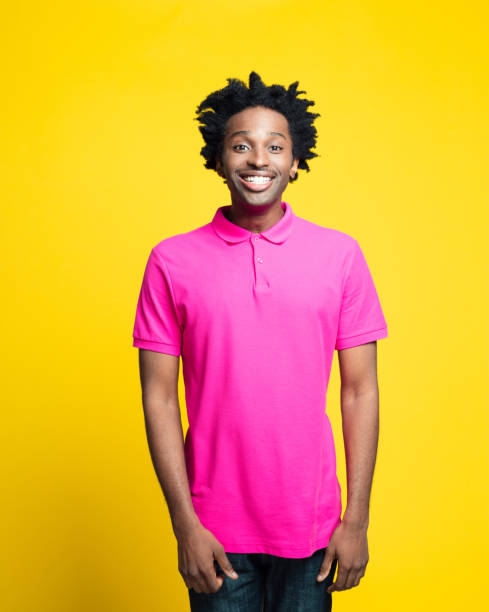 retrato colorido de jovem feliz vestindo camisa polo rosa - polo shirt african ethnicity men african descent - fotografias e filmes do acervo