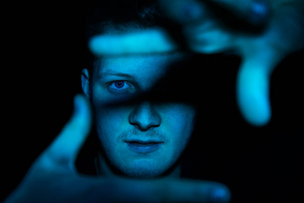 eye contact young man in blue light showing photo frame - light shadow lighting equipment inspiration imagens e fotografias de stock