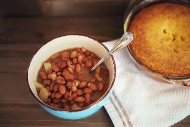 A blue bowl full of southern pinto beans on a wooden table