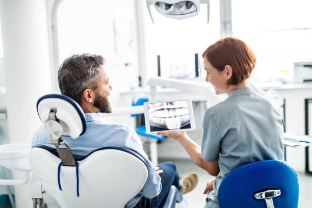 Rear view of man and dentist in dental surgery, annual check-up. A rear view of man and dentist in dental surgery, annual check-up. tablet pc and digital hospital tools stock pictures, royalty-free photos & images