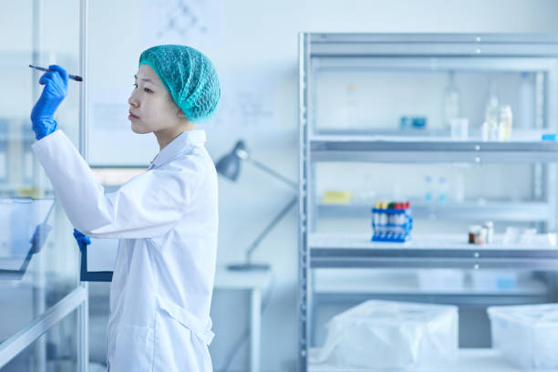 istock Asian Woman Writing Formulae On Glass Wall 1210081319