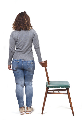 rear view of woman playing with a chair in white background