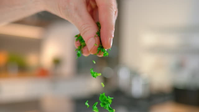 SLO MO TD Chopped parsley falling onto a plate of pasta