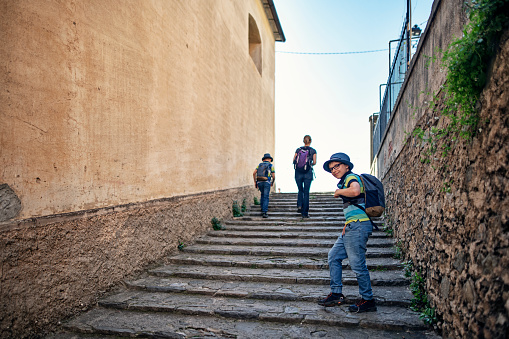 Family sightseeing beautiful Italian town of Corniglia.  One of the five towns in Cinque Terre National Park - a UNESCO World Heritage Site. Tourists are climbing stairs near the small church of Saint Catherine.
Nikon D850