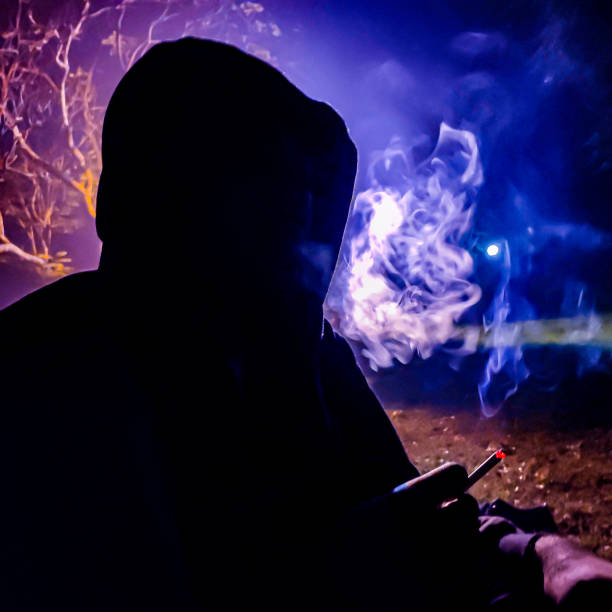 a man in black shadow smoking cigarette in the blue and purple background