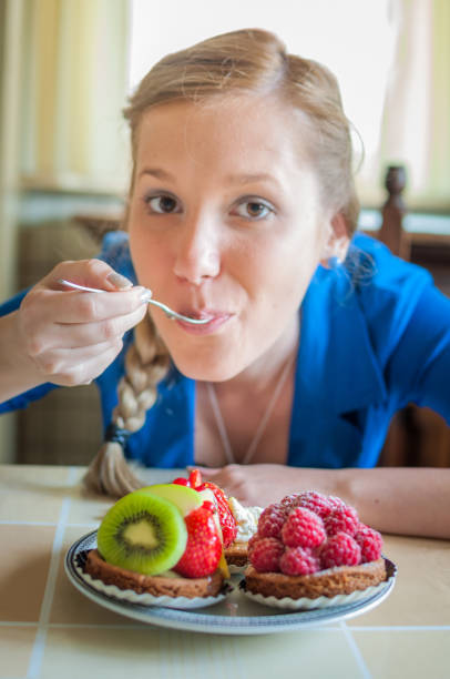 Cropped image of a woman enjoying apple pie with a scoop vanilla ice cream and chocolate sauce in a cafe