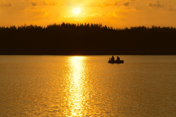 Photo of Fishermen catch fish on the lake at sunset.