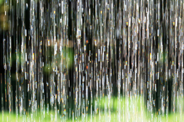 istock Blurred background pouring water vertically with reflective sun highlights in the garden. 1210097787