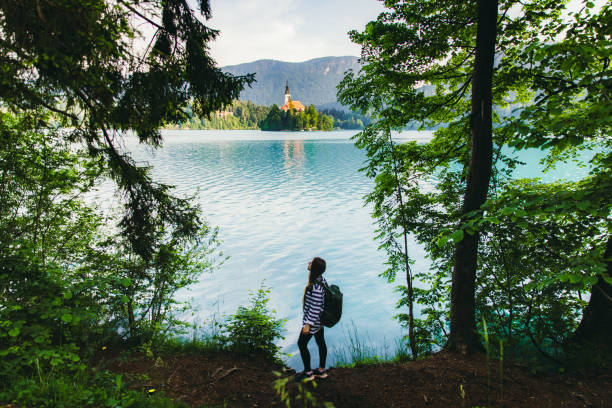 viaggiatore donna che esplora il pittoresco lago di montagna di bled nelle alpi giulie, slovenia - latemar mountain range foto e immagini stock