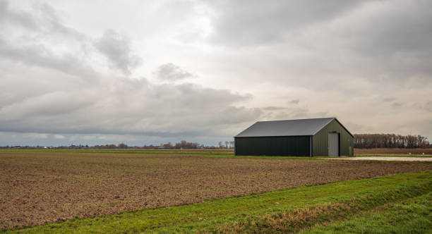 Modern agricultural barn at a plowed field