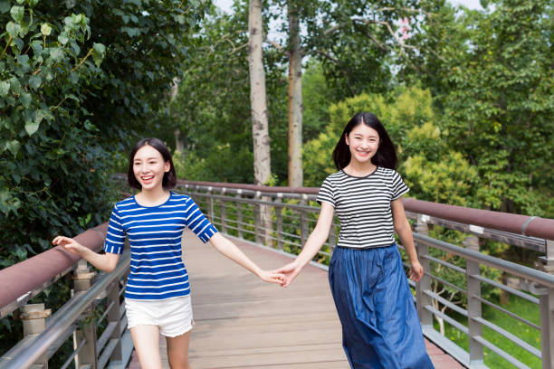 two beautiful girl are good friends, they are walking on the pedestrian overpass
