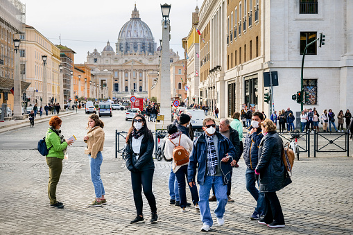 Rome, Italy, February 27 -- A group of tourists with medical masks on their mouths near the St. Peter's Square (in the background), one of the places most visited by millions of people every year in Rome. HD format image.