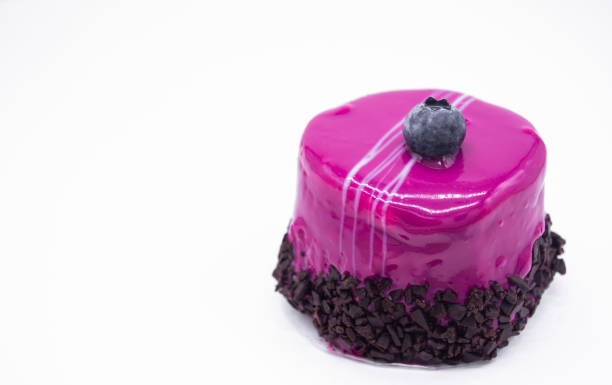 gâteau aux bleuets dans un glaçage rose vif presque violet avec une grande baie de myrtille sur le dessus et une pépite de chocolat au fond. concept de vacances, d’anniversaire, de vie douce, d’amour et de fête. espace de copie - little cakes photos et images de collection