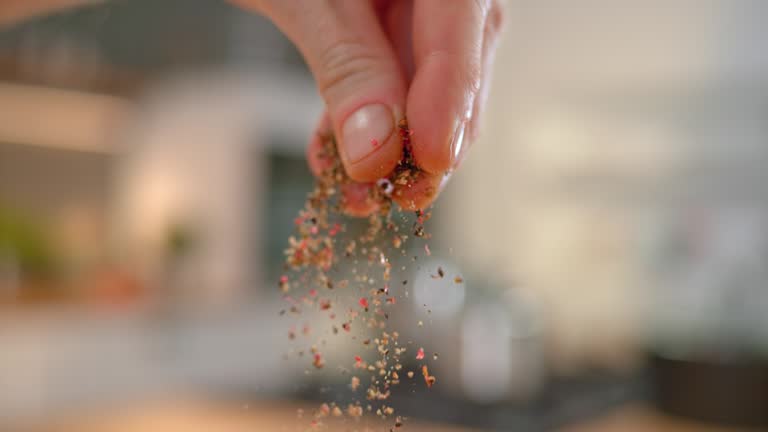 SLO MO LD Person's fingers sprinkling ground pepper