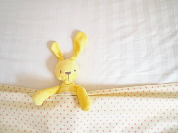 istock yellow rabbit doll laying on white bed 1210115820