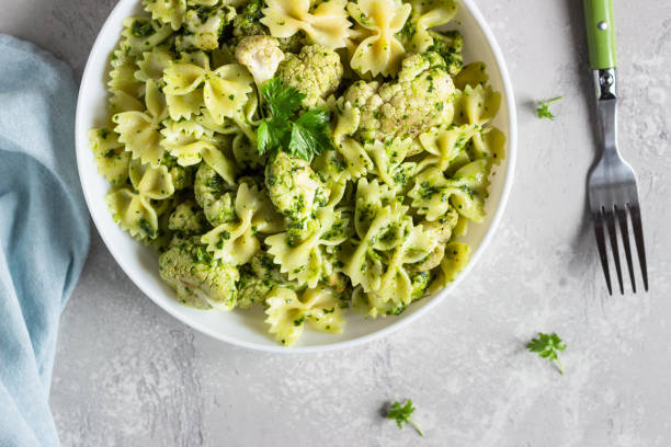 istock Pasta with green sauce and roaster cauliflower on a white plate. Copy space. 1210116670