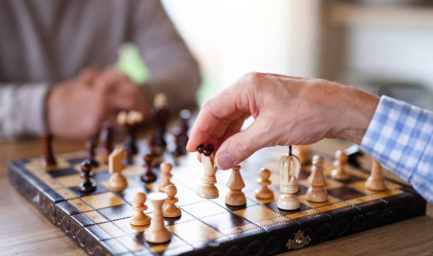 Midsection of senior men friends at home, playing chess. Midsection of unrecognizable senior men friends at home, playing chess. senior chess stock pictures, royalty-free photos & images
