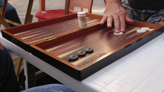 Aged retired men playing backgammon in the outside. board games enjoyment.