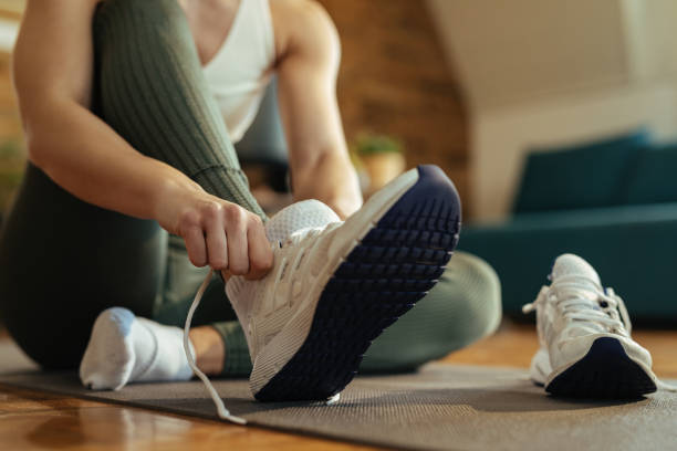 primo posto di donna atletica che si mette le scarpe da ginnastica. - scarpe da ginnastica foto e immagini stock