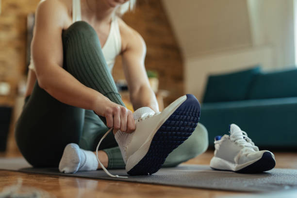 istock Unrecognizable sportswoman putting on sneakers while sitting on the floor. 1210121384